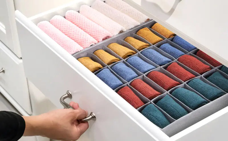Drawer organizer with colorful socks inside a white drawer.