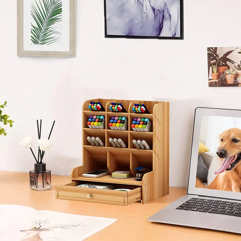 Wooden desk organizer with stationery items on a desk with a laptop displaying a dog image.