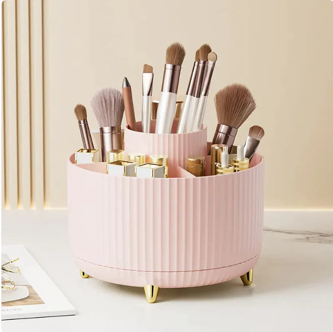 Pink makeup brush holder with various brushes and products on a light background