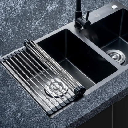 Black kitchen sink with a stainless steel grid on a dark kitchen countertop