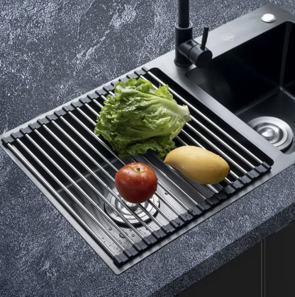 Stainless steel sink with a grid and vegetables on a dark countertop